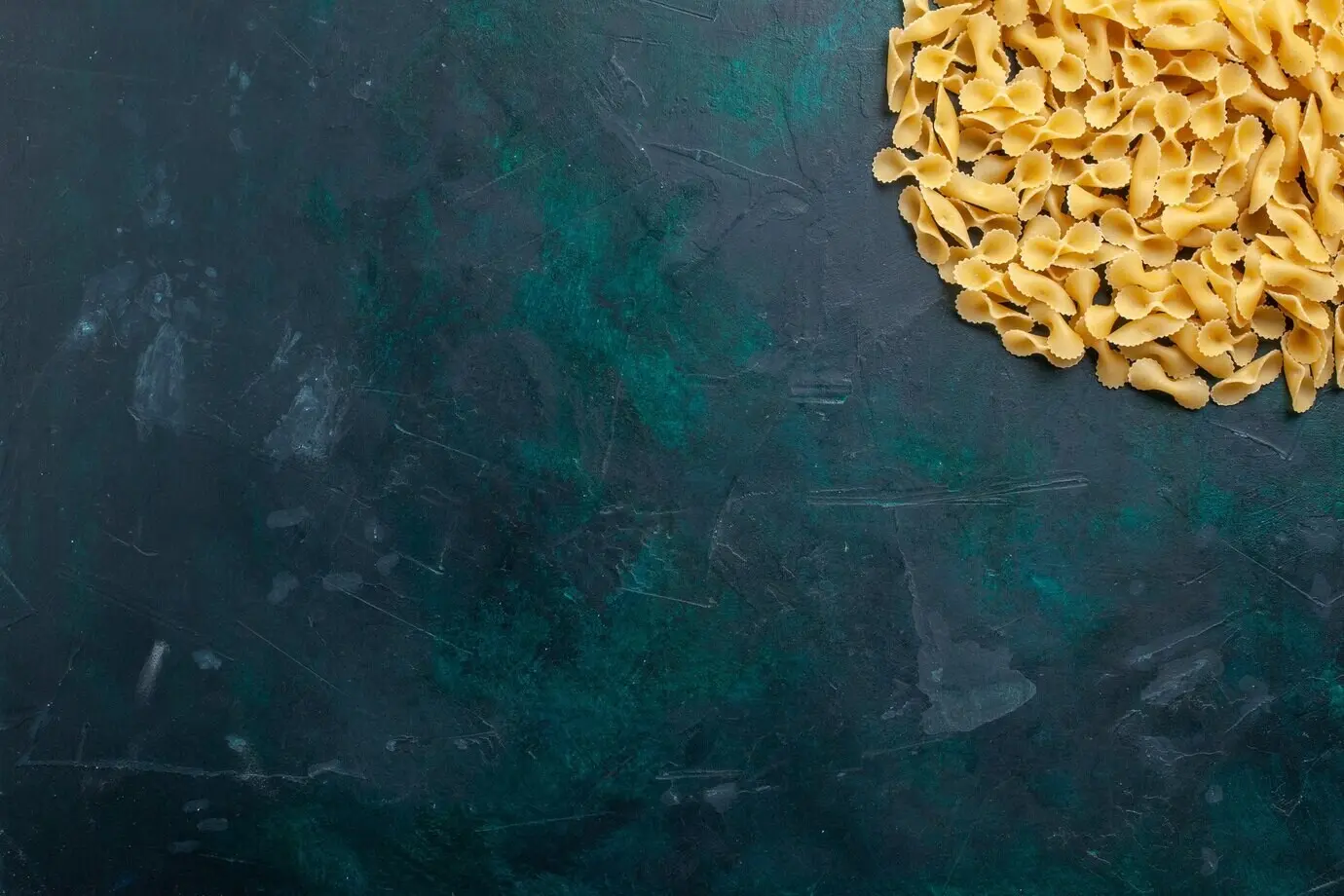 Draufsicht auf gelbe, rohe italienische Pasta auf einem dunkelblauen Schreibtisch.